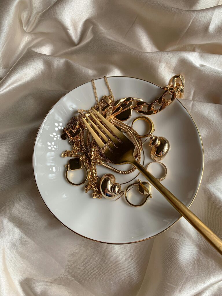 luxurious gold jewellery on a ceramic plate with satin fabric backdrop.