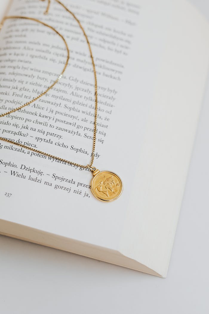Gold necklace elegantly draped over an open book, creating a serene and minimalistic aesthetic.